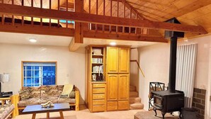 A cozy living room with a sofa, coffee table, wooden cabinet, and a fireplace.