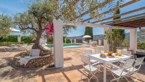 Eine Terrass mit Pool, weißen Möbeln und einer Pergola.