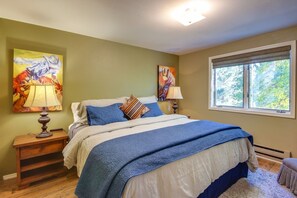 A bedroom with a bed, two nightstands, a window, and two wall-mounted lamps.