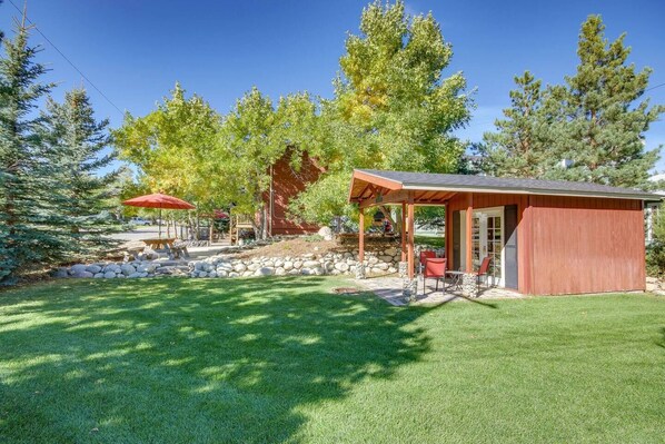 A covered patio area with outdoor seating, a stone wall, and a red building.