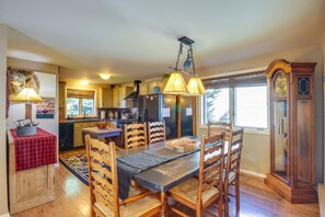A kitchen with wooden cabinets, a dining table with chairs, a chandelier, and a clock.