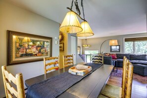 A dining area with a long table, chairs, and a chandelier.