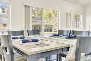 Ein Essbereich mit einem langen Tisch, Stühlen und Blick durch große Fenster.