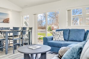 Ein modernes Wohnzimmer mit einem blauen Sofa, einem runden Couchtisch und einem Essbereich mit Stühlen und einem Tisch.
