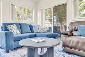 A room with a blue sofa, a brown leather chair, and a round table with a book.