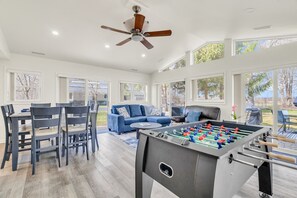 A spacious indoor area with a foosball table, a ceiling fan, and a dining table with chairs.
