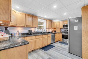 Eine moderne Küche mit Holzausstattung, einem Edelstahlkühlschrank und einem eingebauten Backofen.