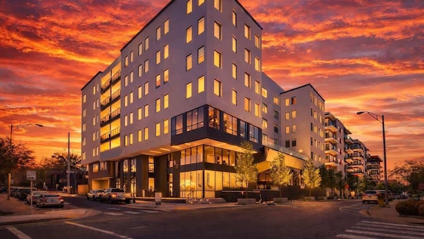 Een modern hotel met een opvallende hoekingang, meerdere verdiepingen en een grote glazen gevel.