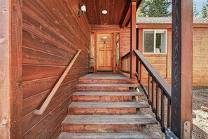 Eine Holztreppe führt zu einer Tür mit einem Fenster, umgeben von Holzwänden und einem Geländer.