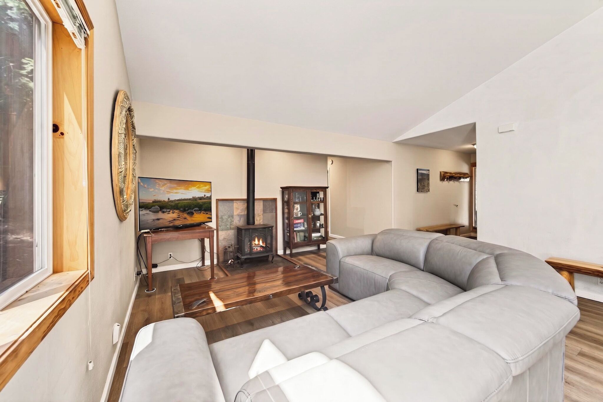 A living room with a sectional sofa, a fireplace, a wooden coffee table, and a painting on the wall.
