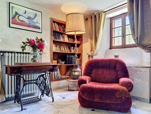 Ein gemütliches Zimmer mit Bücherregal, einem roten Sessel, einer Heizung und einem Bild an der Wand.