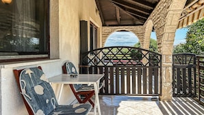Un espacio de estar al aire libre techado, con una mesa, sillas, un portón decorativo y vistas del paisaje circundante.
