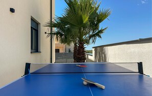 Ein blauer Tischtennis-Tisch mit Netz, Schläger und Ball.
