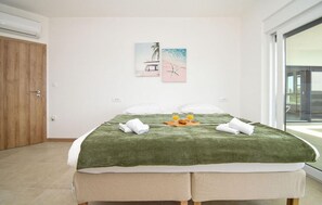 Ein Schlafzimmer mit Bett, einer Holztür, einer wandmontierten Klimaanlage und einem Fenster.