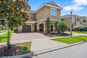A residential house with a driveway, a garage, and a well-maintained lawn. - Fairway Royal Cottage: Near Disney, Golf Course View, Theater (Kissimmee)