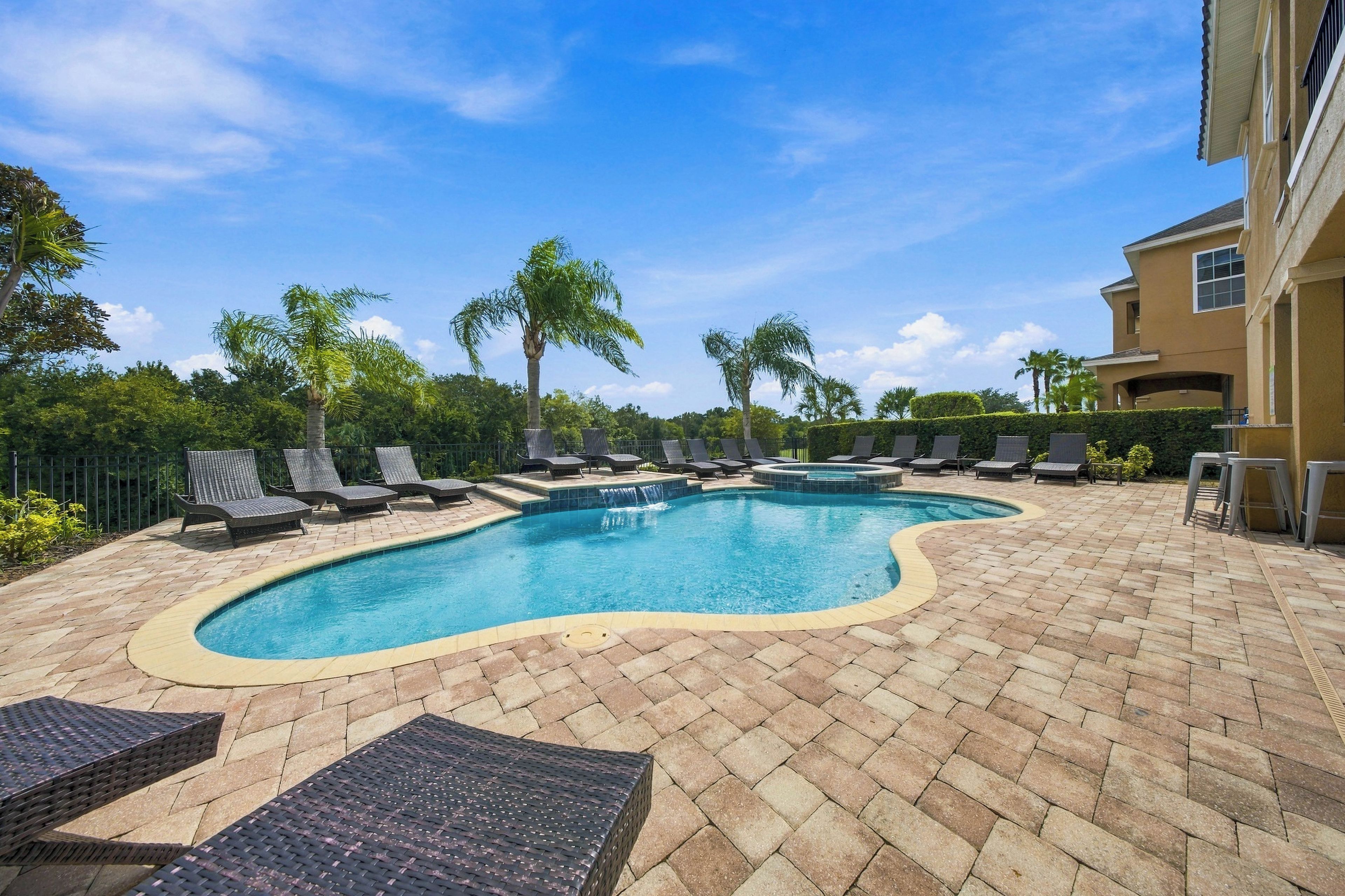 A swimming pool with lounge chairs and a tiled deck.