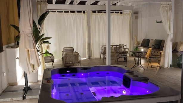 A hot tub with a built-in lighting system, surrounded by outdoor furniture and a covered patio area. - PALAZZO SOSPIRI (Bisceglie)
