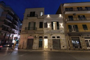 Un edificio de varios pisos con balcones, acceso en la planta baja y una puerta visible.