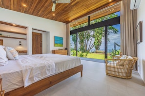 Ein Schlafzimmer mit einem großen Bett, Holzboden und Blick ins Freie.