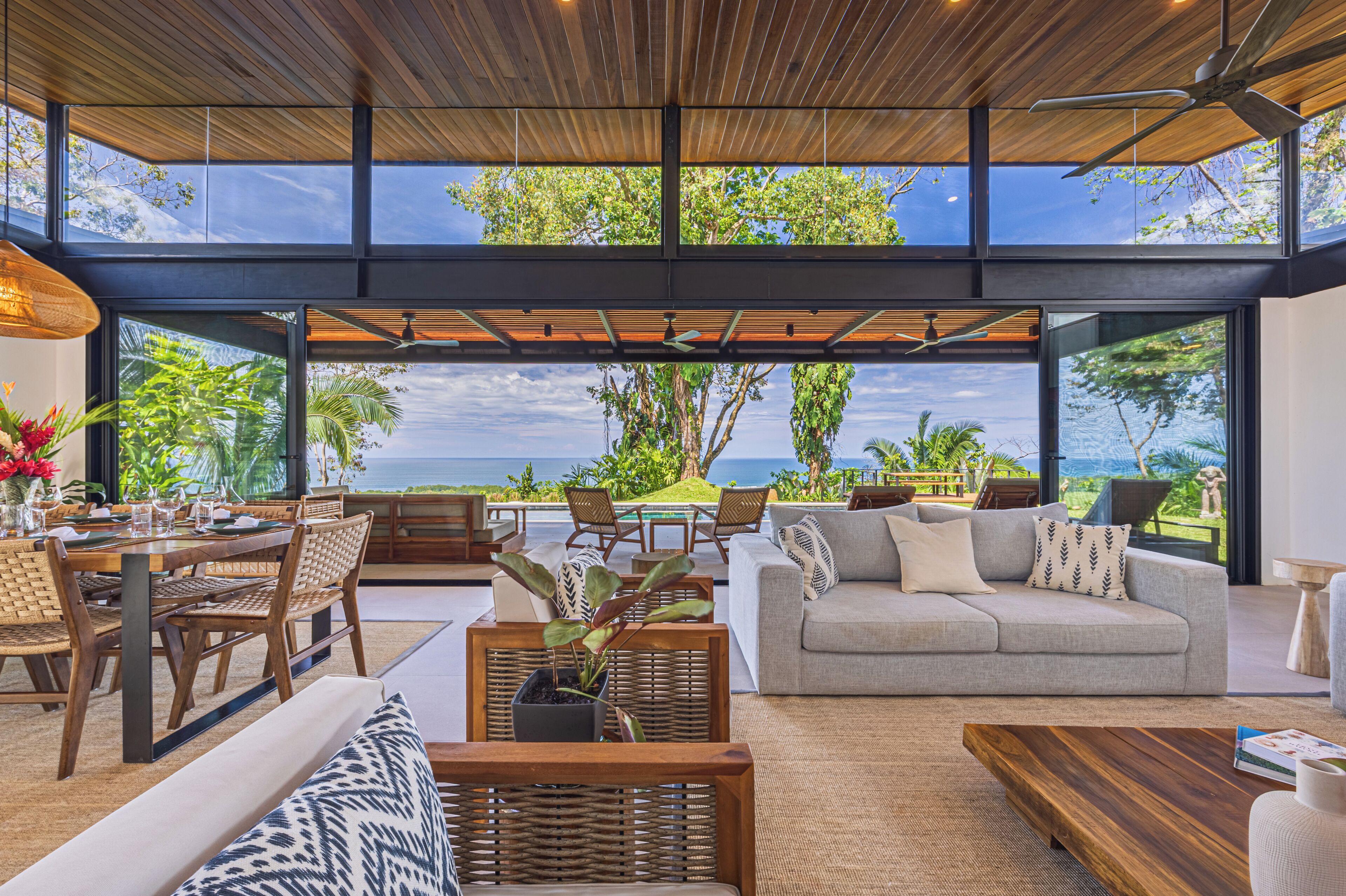 A spacious living area with a large window overlooking a scenic view, furnished with a sofa, chairs, and a dining table.