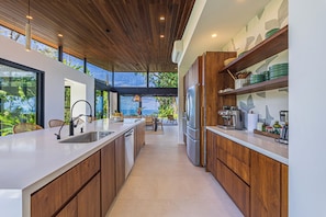 Eine moderne Küche mit Holzschränken, einer großen Kochinsel inklusive Spüle und einem eingebauten Kühlschrank.