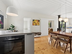Eine moderne Küche mit Geschirrspüler, ein Essbereich mit Holztisch und Stühlen sowie ein Blick ins Freie.
