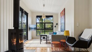 Uma sala de estar moderna com uma lareira a lenha, um sofá, uma mesa de centro e uma televisão.
