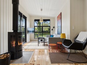 Ein modernes Wohnzimmer mit Kaminofen, einer Couch, einem Couchtisch und einem Fernseher.