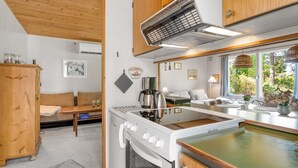 Een kleine keuken met een kookplaat, oven en een eethoekje met een tafel en stoelen.
