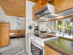 Eine kleine Küche mit Herd, Backofen und einer Essecke mit Tisch und Stühlen.