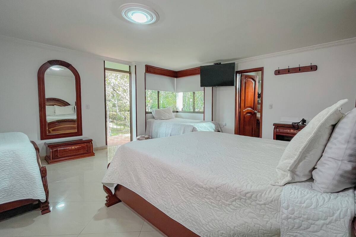 A bedroom with a large bed, a smaller bed, a TV, and a door leading to a balcony.