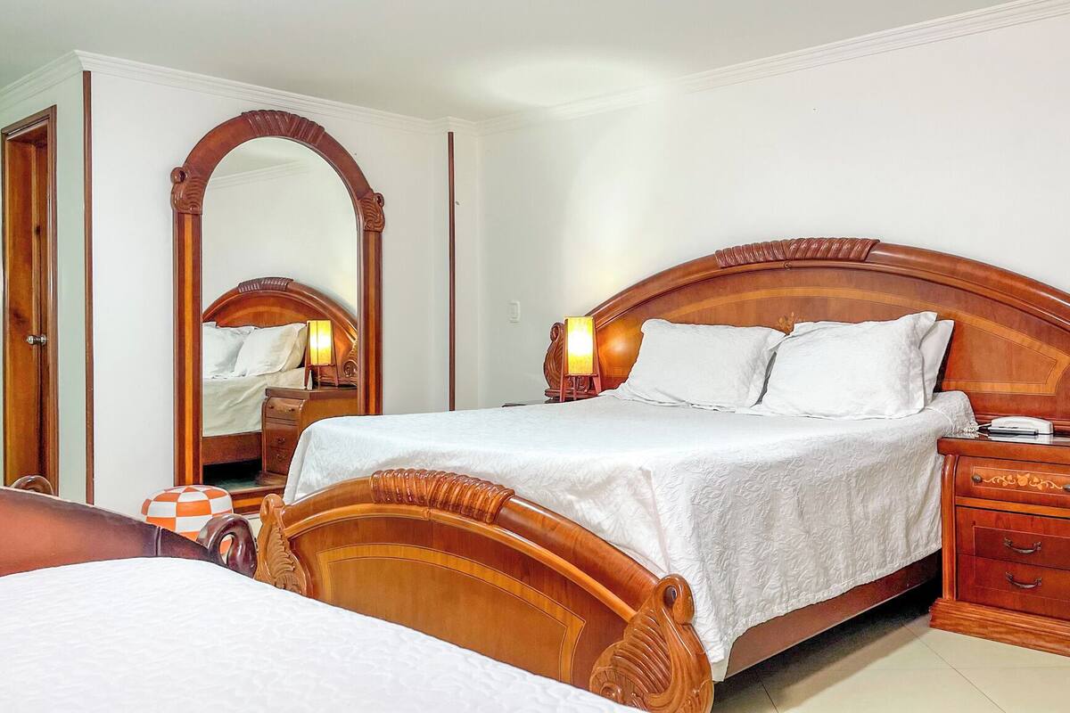 A wooden four-poster bed with a nightstand and a mirror.