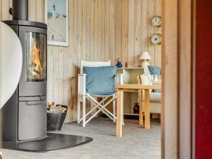 A cozy room with a wood-burning stove, a white chair, a small table, and a lamp. - "Jürgen" - 2.5km from the sea by Interhome (Blokhus)