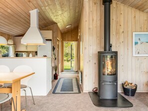 A cozy cabin interior with a central wood-burning stove, a kitchen area, and a dining space. - "Jürgen" - 2.5km from the sea by Interhome (Blokhus)