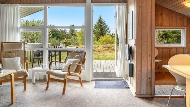 Interior de madera con ventanas amplias, un comedor y una zona de estar.