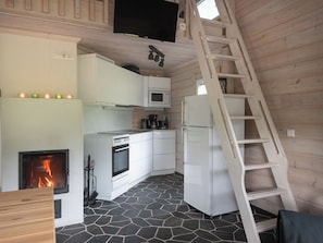A compact kitchen with a stone floor, a fireplace, a microwave, and a refrigerator. - Virtaan virtavilla by Interhome (Sysmä)