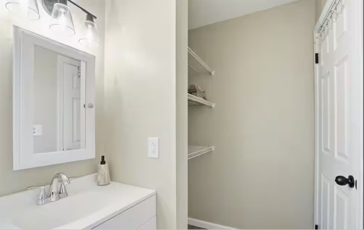 A bathroom with a white vanity, a mirror, and a shower area with a door.