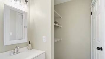 A bathroom with a white vanity, a mirror, and a shower area with a door.