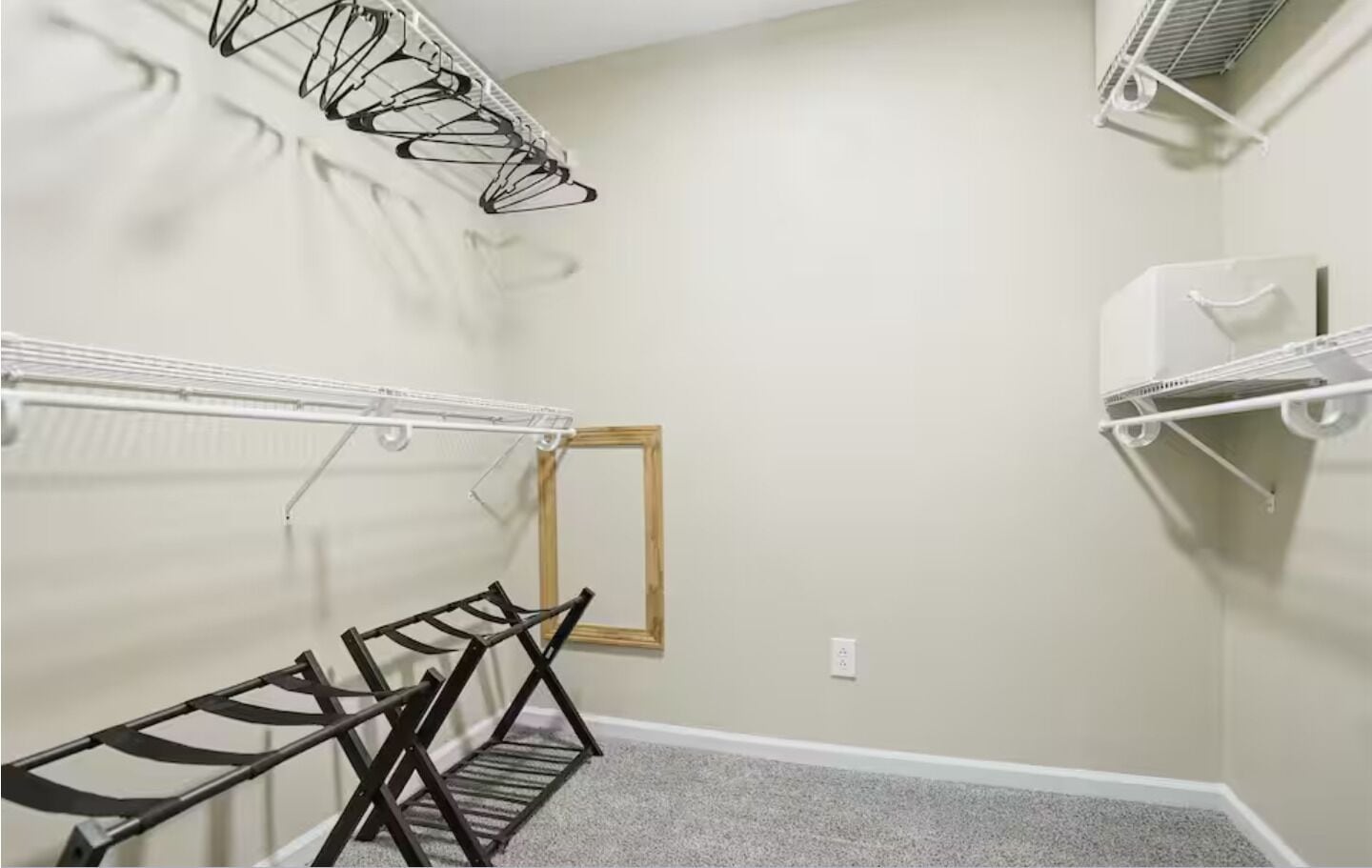 Un dressing avec une étagère en métal, une étagère en bois et un tableau encadré accroché au mur.