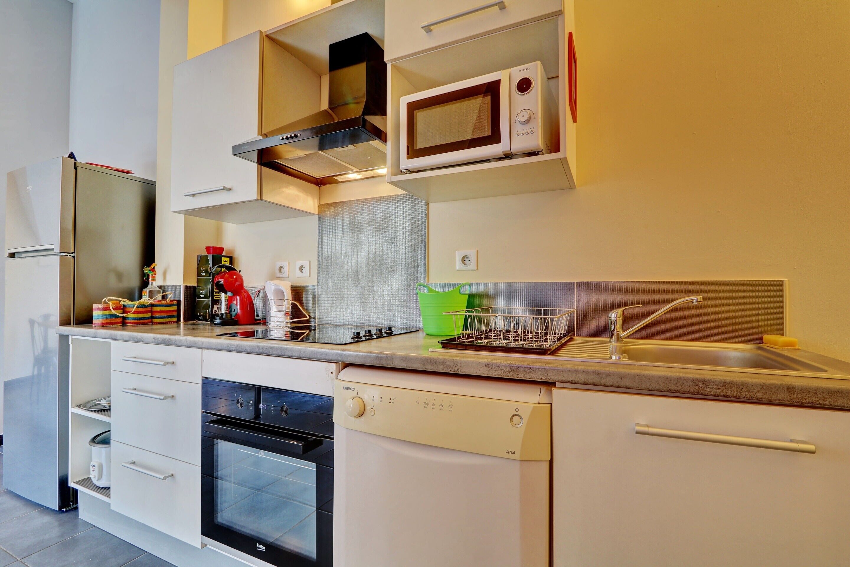 Una cocina moderna equipada con lavavajillas, horno, microondas y una campana extractora de acero inoxidable.