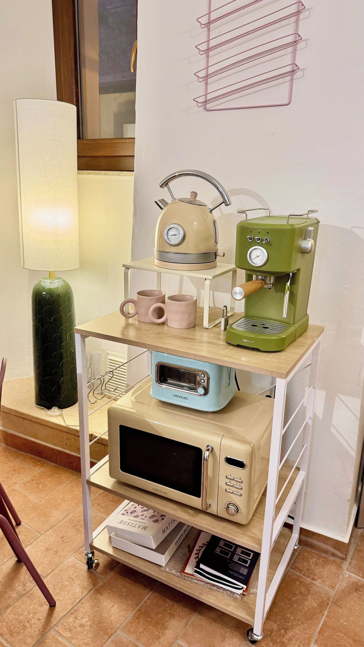 Un angolo cottura con macchina da caffè, bollitore e forno a microonde su un carrello.