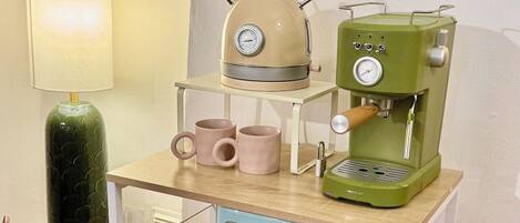 Una kitchenette con cafetera, hervidor y microondas sobre un carrito.