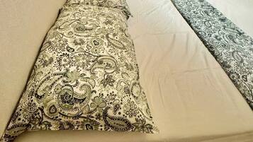Una stanza con un letto, un armadio, una lampada e un termosifone.