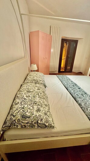 A room with a bed, a wardrobe, a lamp, and a radiator. - Pink House - InBorgo (ACQUASPARTA)