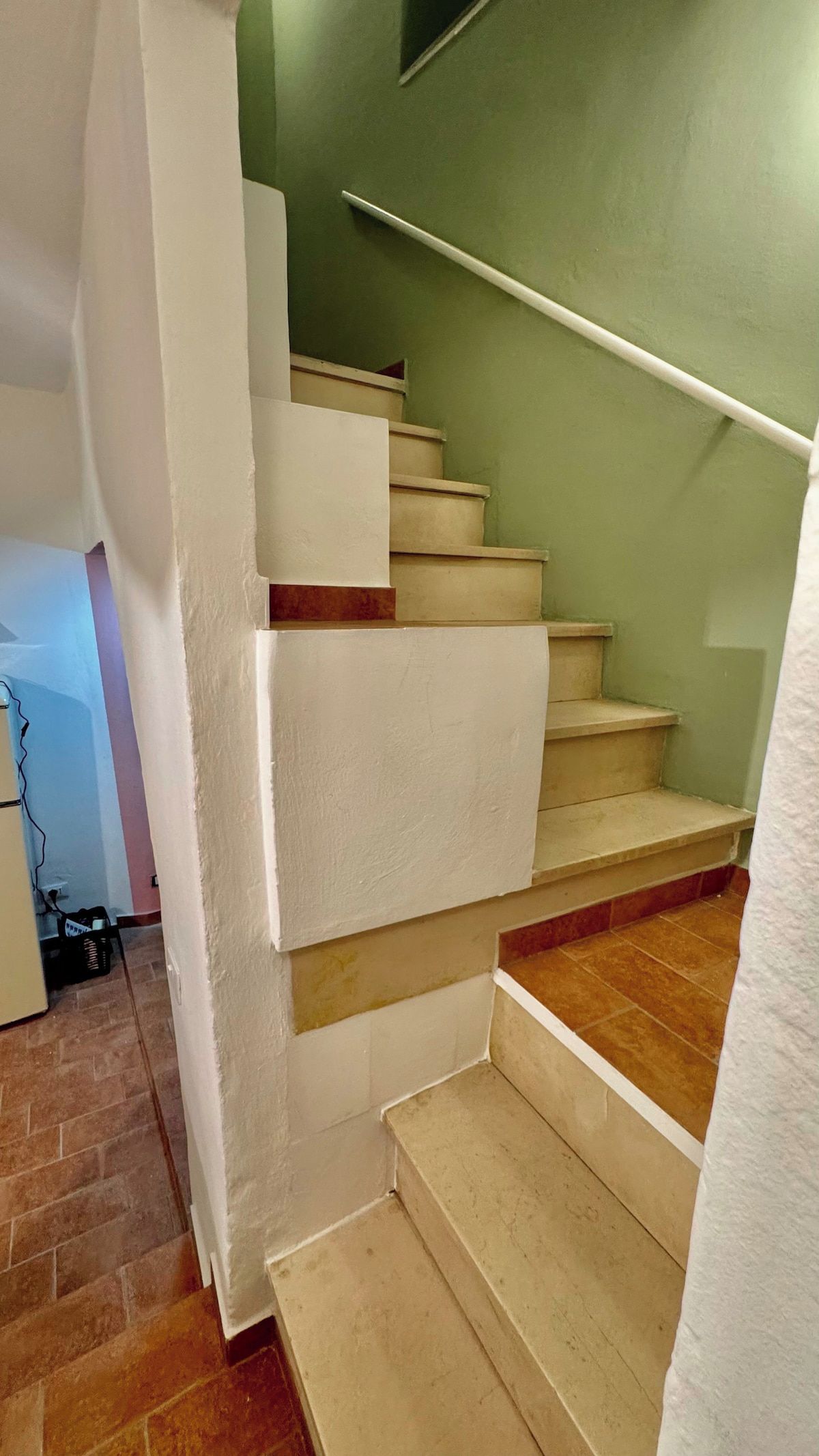 A staircase with white walls and beige steps leading to a higher floor.