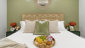 Una cama bien hecha con una bandeja de desayuno, almohadas y un cabecero de madera.
