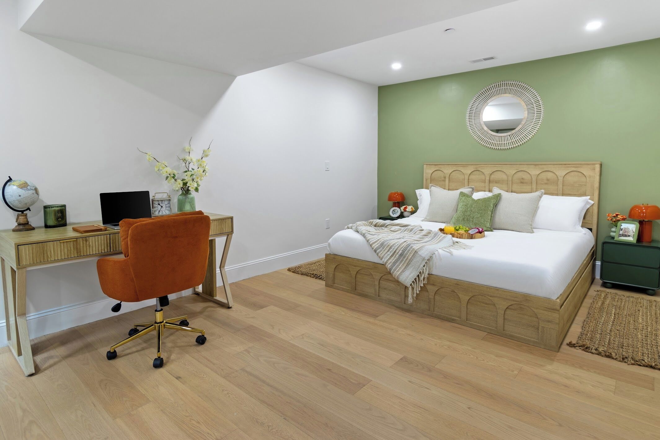 Une chambre à coucher avec un lit, un bureau, une chaise et un miroir au mur.