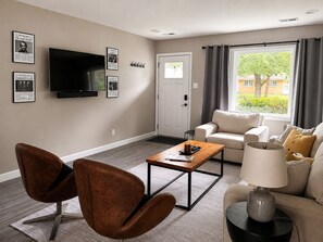 A living room with a TV, a sofa, a coffee table, and a lamp. - The Cat Haus - Across the street from the Stadium! (Manhattan)