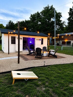 A small outdoor structure with a fire pit, seating, and string lights. - The Cat Haus - Across the street from the Stadium! (Manhattan)