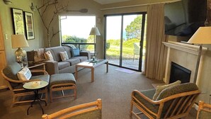 Ein Wohnzimmer mit einer Couch, Sesseln, einem Couchtisch, einem Kamin und einem Fernseher.